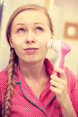 Woman using facial cleansing brush on face