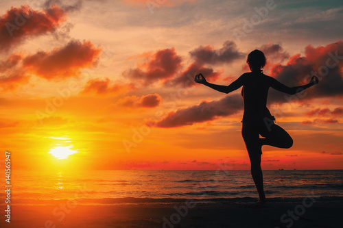 Fototapeta Naklejka Na Ścianę i Meble -  Silhouette young woman practicing yoga on the beach at sunset.
