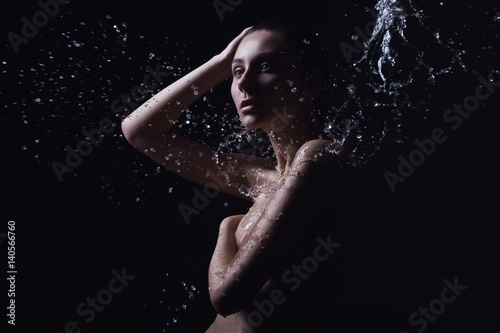 Portrait of a beautiful young woman with splashes of water