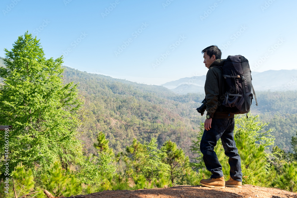 Man Traveler with photo camera and backpack hiking outdoor Travel Lifestyle and Adventure concept.