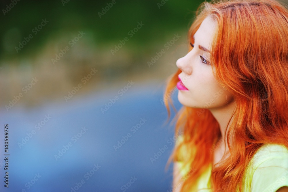 Portrait of a very beautiful serious brown eyed girls with bright red hair in a light green dress on a background of lake, close-up Portrait of a very beautiful serious brown eyed girls with bright red hair in a light green dress on a background of lake, close-up