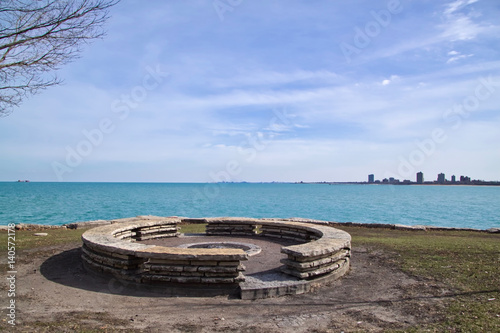 Fire pit located on Lake Michigan shoreline in Chicago's south side park with view of southern cityscapes