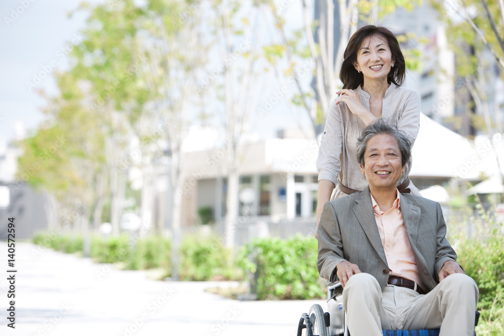 Mature woman pushing senior man on wheelchair Mature woman pushing senior man on wheelchair