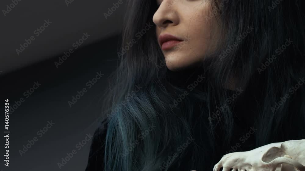 Portrait of a young girl holding a mysterious skull in the hands of a fox. Painted long hair.