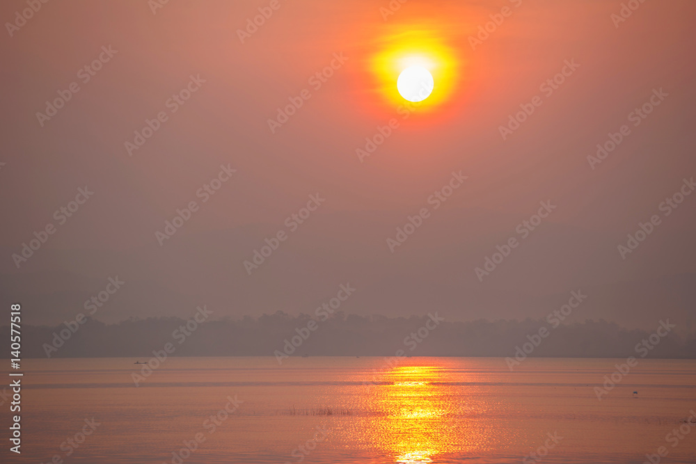 Sunrise over the lake with silhouette branch in foreground 