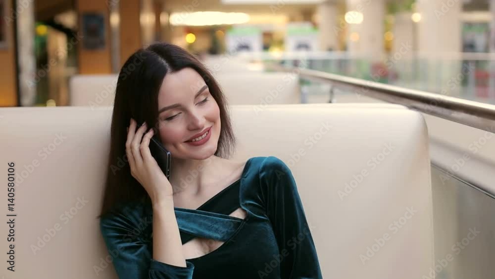 Happy female shopper talking on the phone sitting in a cafe and smiling. Happy female shopper talking on the phone sitting in a cafe and smiling.