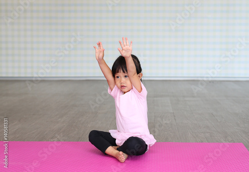 Cute toddler girl practicing yoga and doing exercise