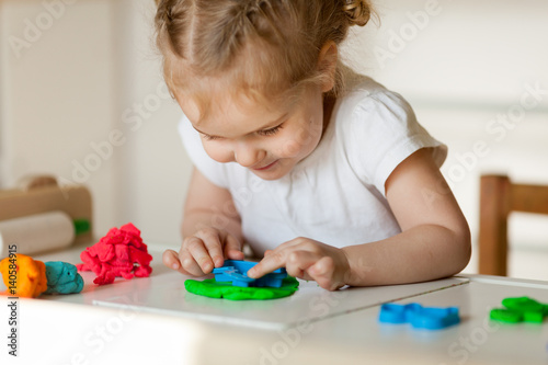 Pretty little girl sculpts from plasticine, indoor