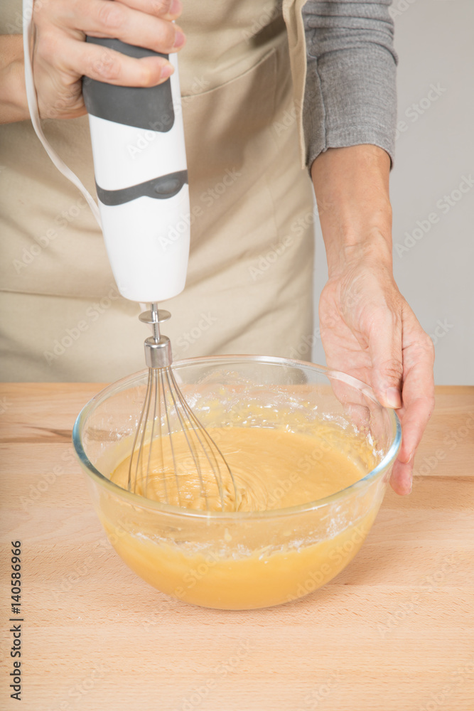 adult woman hands whipping cream in glass bowl with electric mixer to cook a sponge cake
adult woman hands whipping cream in glass bowl with electric mixer to cook a sponge cake