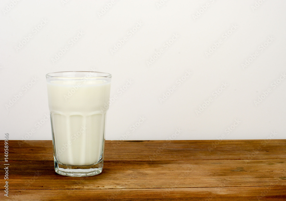 A glass of milk over white background on a wooden surface A glass of milk over white background on a wooden surface