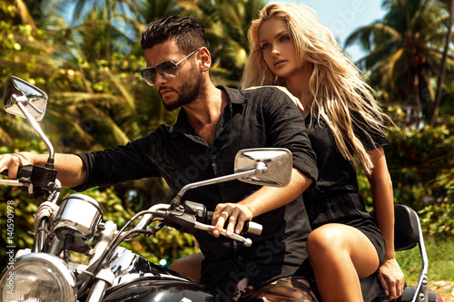 Man riding on a motorcycle with girlfriend on road.