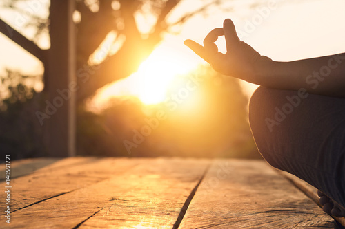 Hand of woman practicing meditation yoga on the nature at sunset