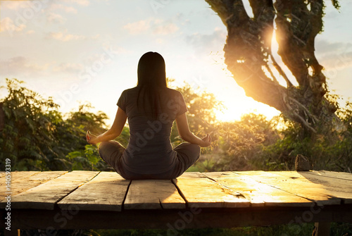 Woman practicing meditation yoga on the nature at sunset