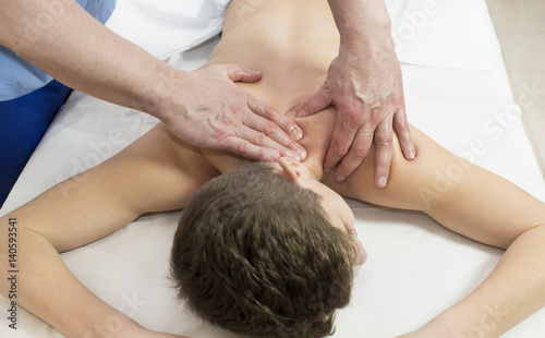 Boy teenager on the procedure of medical medical sports body massage 