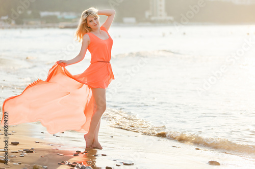Beautiful girl in a red dress on the beach. Concept of femininity, harmony. photo