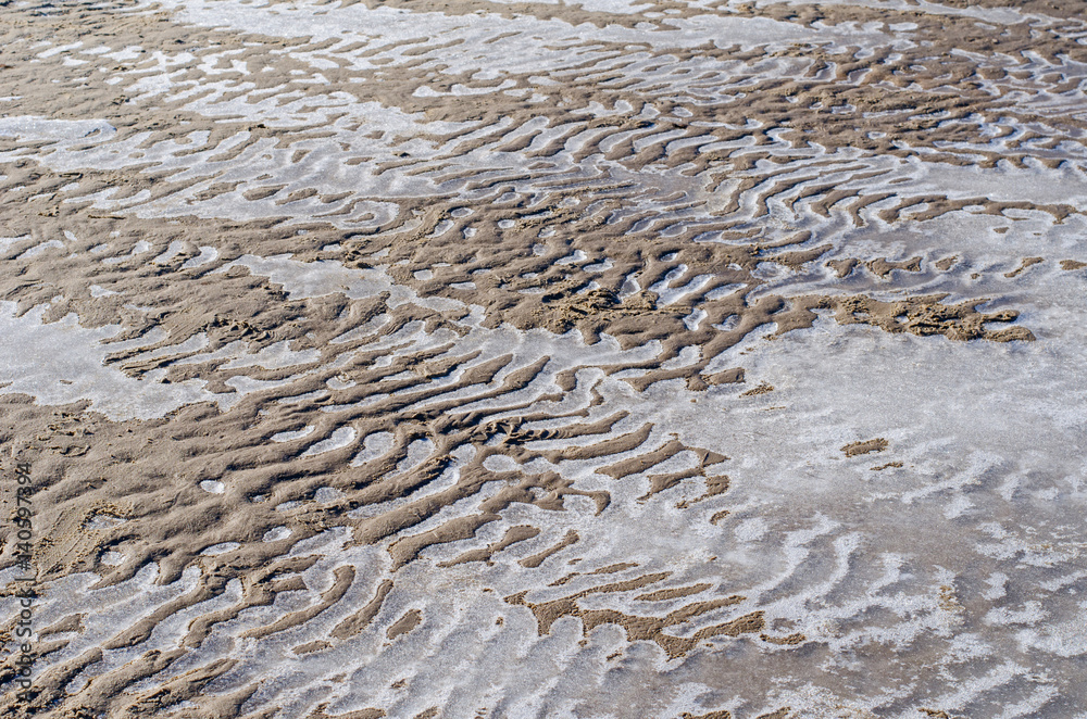 small sand dunes at the shore overlaid with frozen water of the Baltic sea
