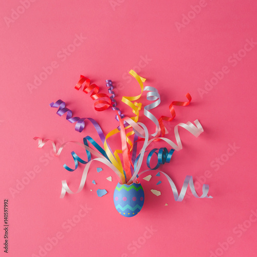 Egg with party streamers on pink background. Easter concept. Flat lay.