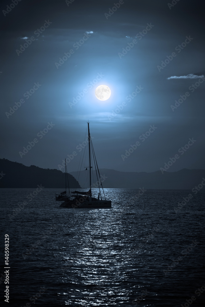 Catamaran sailing in the sea during a full moon