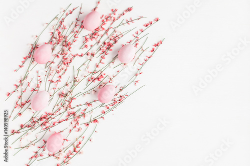 Easter eggs and pink flowers on white background. Easter, spring concept. Flat lay, top view