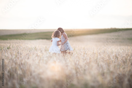 Fototapeta Naklejka Na Ścianę i Meble -  Emotional sisters on wheat field at sunset