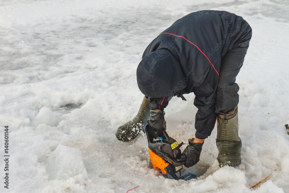 Man cutting chainsaw shell in ice Man cutting chainsaw shell in ice