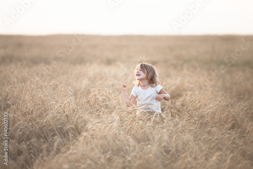 Funny girl dances in field with rye at sunset