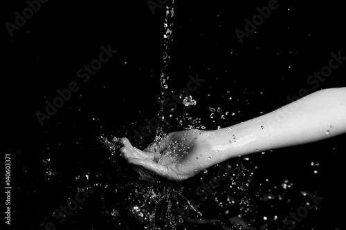 water throwing to a young girl in hands and face with black background 