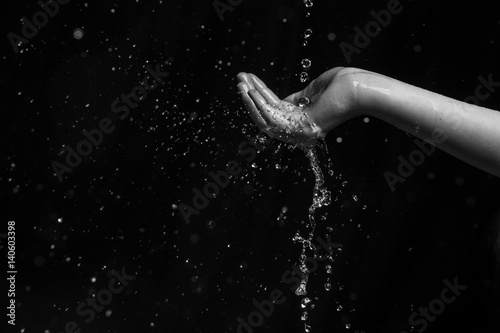 water throwing to a young girl in hands and face with black background  