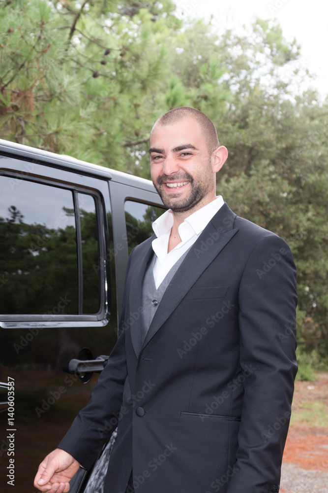 Handsome outdoor businessman with his suit next to his beautiful black car Handsome outdoor businessman with his suit next to his beautiful black car