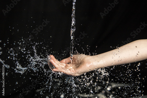 water throwing to a young girl in hands and face with black background  