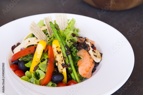 Salad with salmon on black table