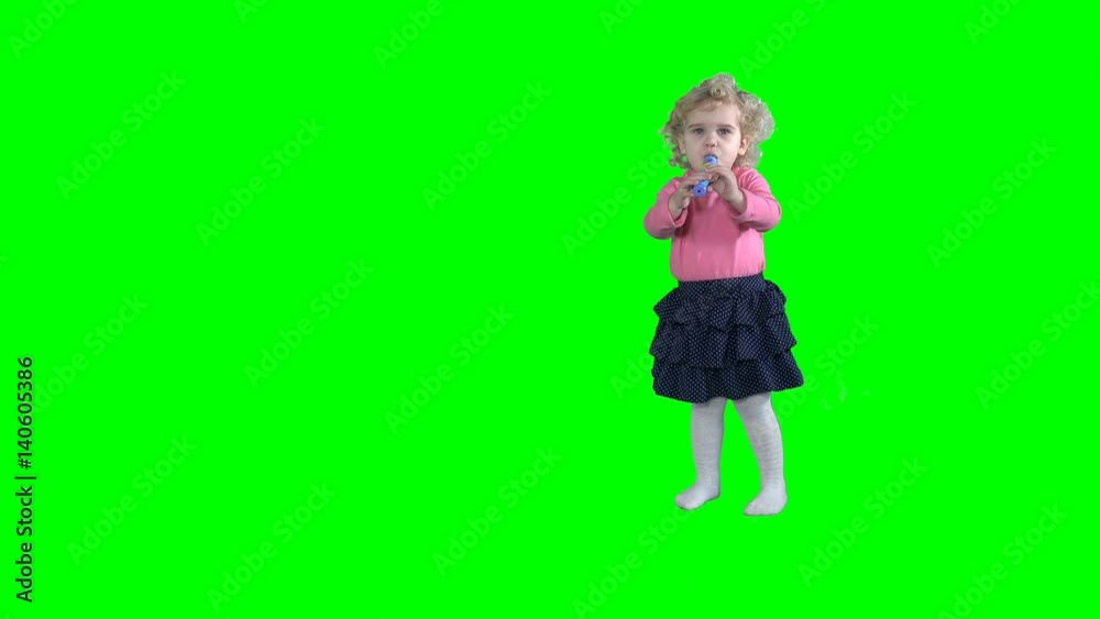 Cute girl child playing with fife pipe and turn around isolated on green Cute girl child playing with fife pipe and turn around isolated on green