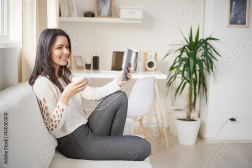 woman reading / listening music using tablet / laptop at home © chika_milan