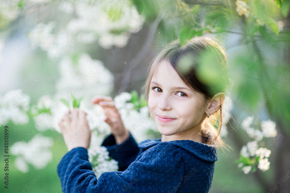 Adorable little girl in blooming apple tree garden. Cute child near apple tree at spring. Adorable little girl in blooming apple tree garden. Cute child near apple tree at spring.