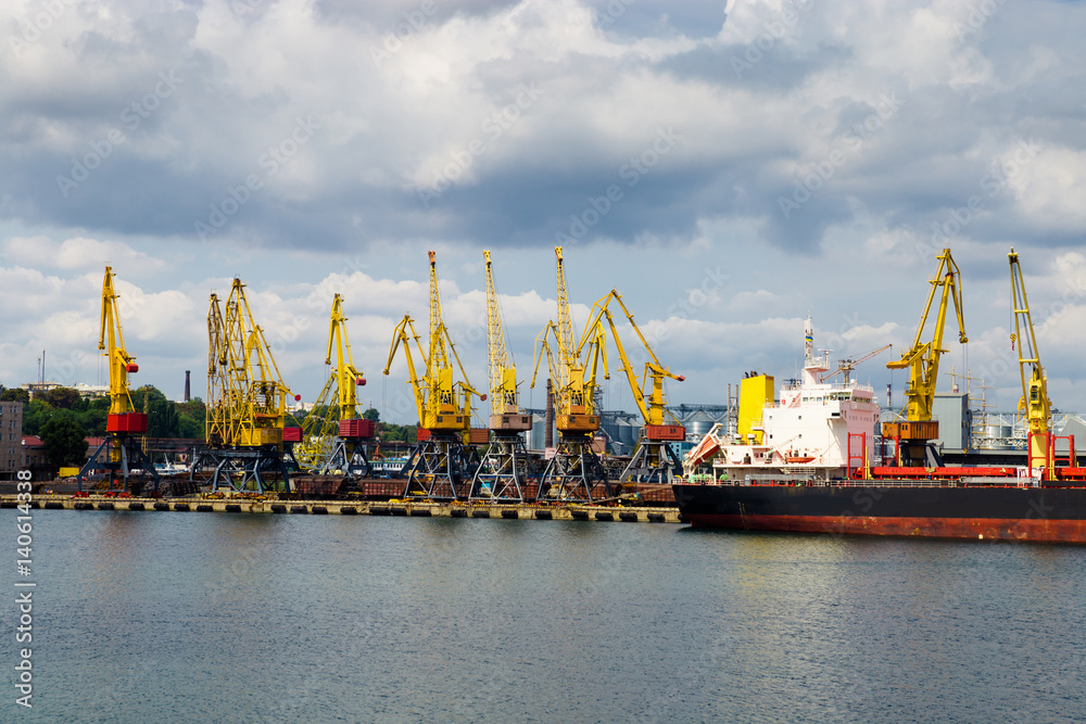 Port cargo cranes over the cloudy sky background