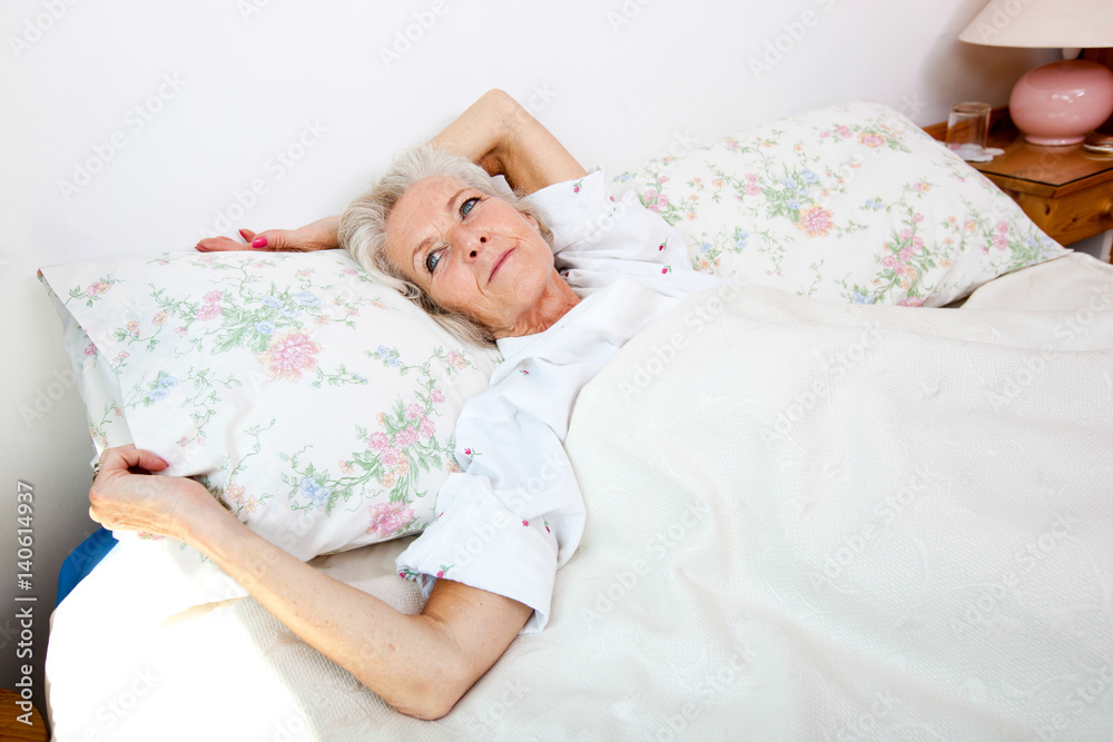 High angle view of senior woman looking away while lying in bed at home High angle view of senior woman looking away while lying in bed at home