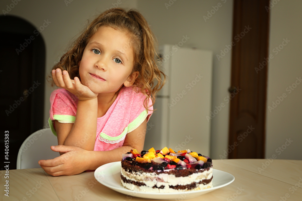 Cute little girl going to taste sweet cake left on kitchen table Cute little girl going to taste sweet cake left on kitchen table