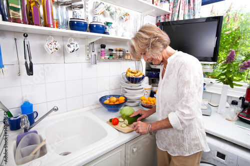 Senior woman chopping fresh vegetable while cooking at kitchen counter