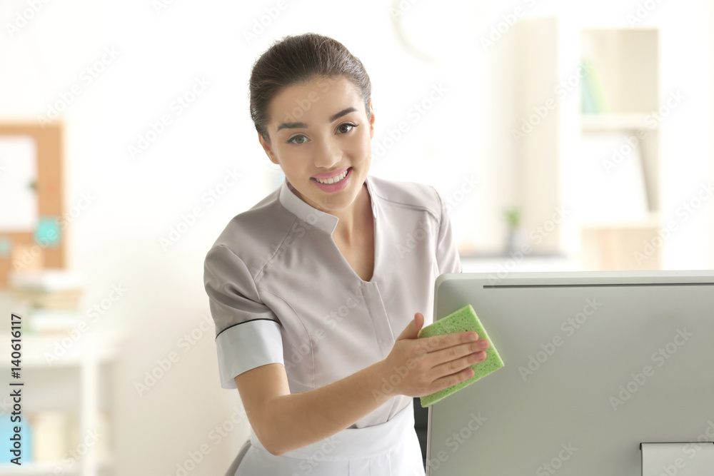 Beautiful young charwoman wiping pc monitor in office Beautiful young charwoman wiping pc monitor in office
