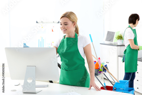 Young woman cleaning computer monitor