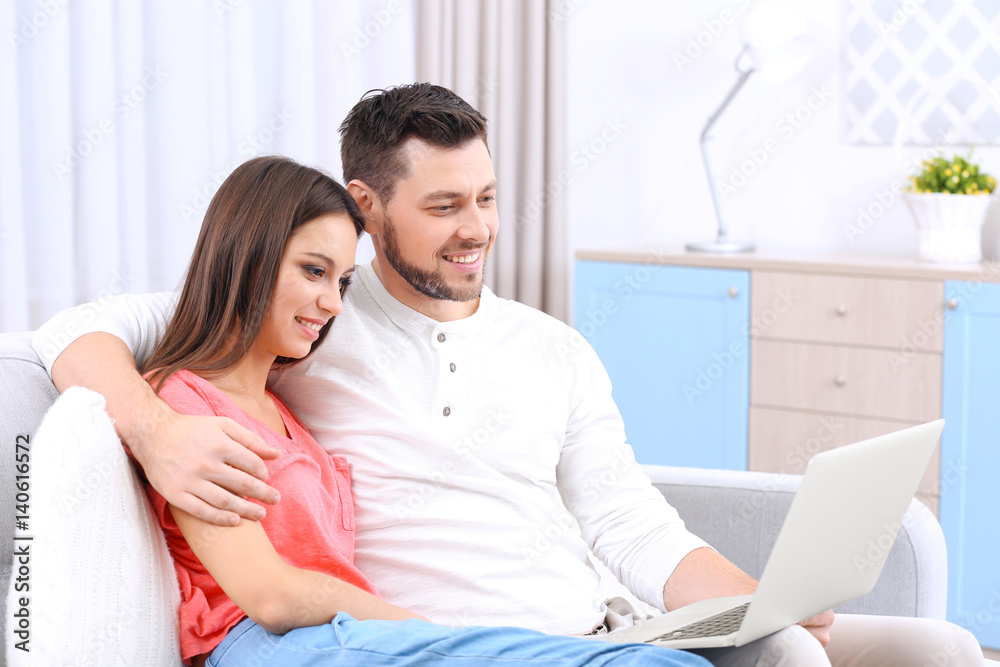 Young couple with laptop on sofa in the room Young couple with laptop on sofa in the room