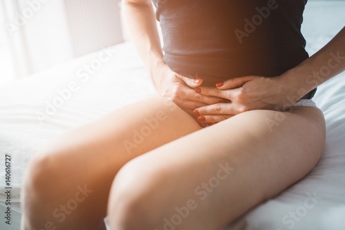 Woman suffers from menstruation pain or stomach ache photo