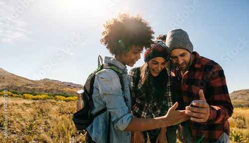 Young hikers looking at pictures on mobile phone