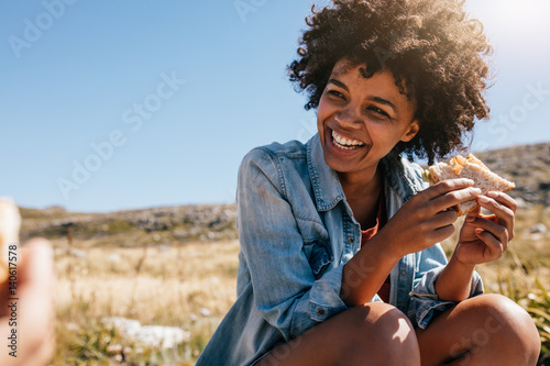 Happy young woman taking break during country hike.