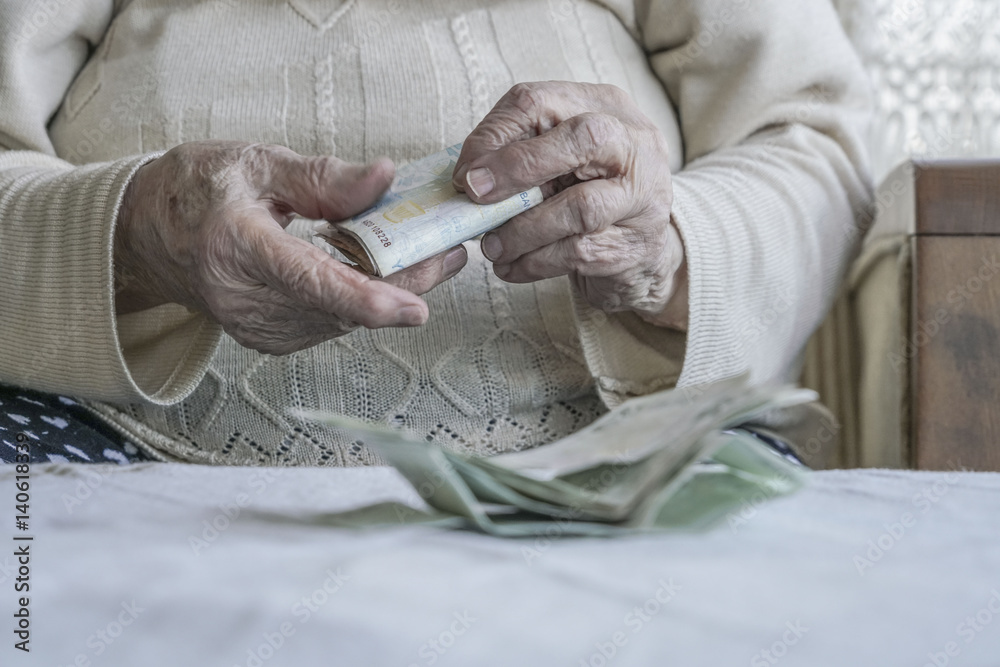 Closeup of wrinkled hands counting turkish lira banknotes