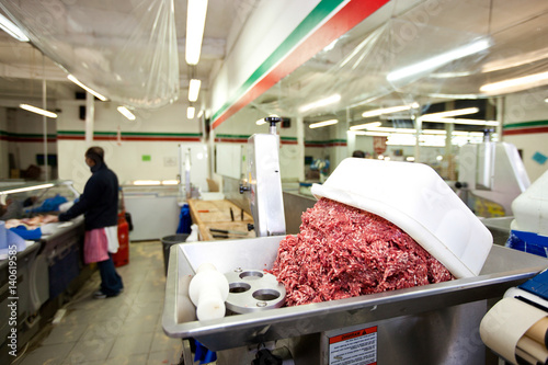 Fotografie Minced meat in container with employee standing in background at store