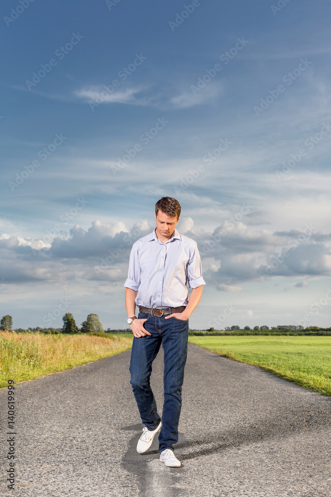 Full length of young man walking on empty rural road Full length of young man walking on empty rural road