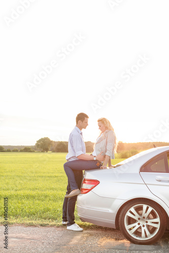 Full length side view of romantic young couple by car at countryside © moodboard