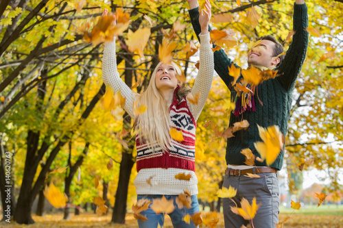 Couple enjoying falling autumn leaves in park