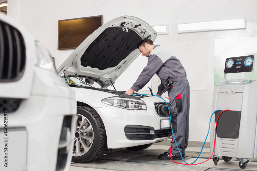 Full length of male engineer examining car in automobile repair shop Full length of male engineer examining car in automobile repair shop